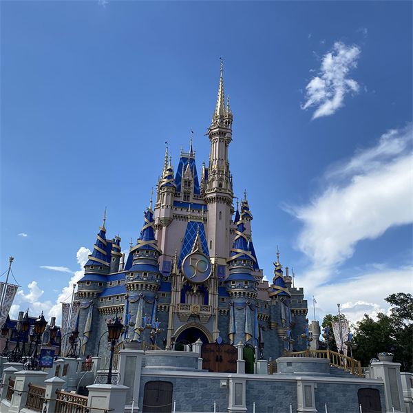 Cinderella Castle at Walt Disney World under a bright blue sky, carrying the gold 50th anniversary crest.